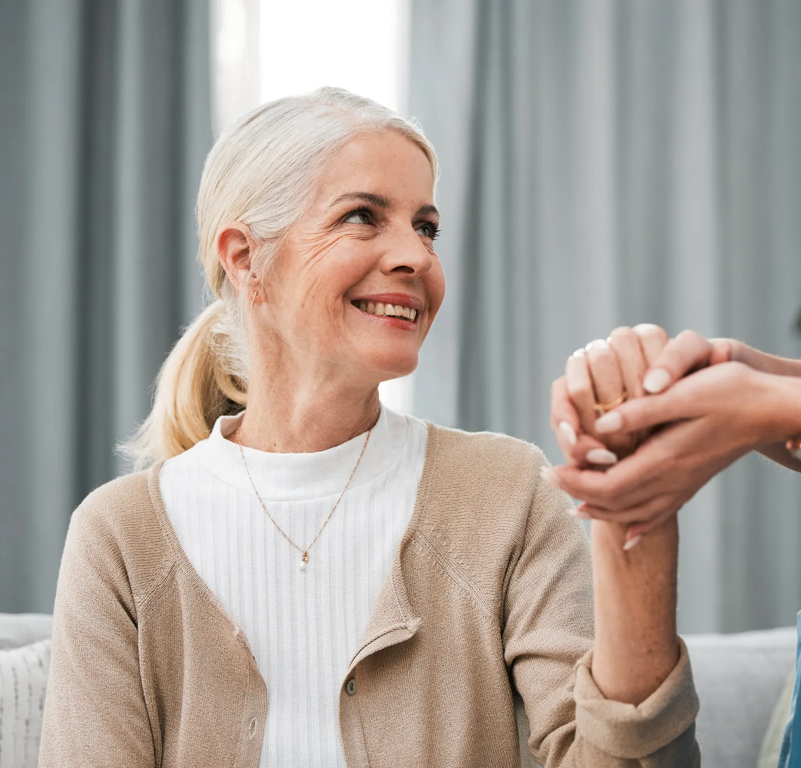 Lächelnde Seniorin hält die Hände einer Pflegekraft